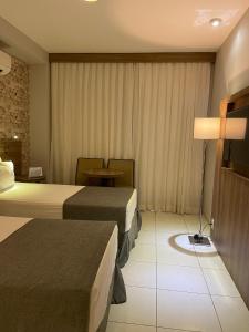 una camera d'albergo con due letti e un tavolo di Promenade Fusion Itaguaí a Itaguaí