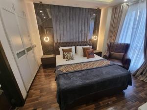 a bedroom with a large bed and a chair at Elysium Service Apartment in Islamabad