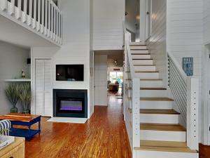 a white staircase in a living room with a fireplace at The Last Dollar Cottage in Topsail Beach