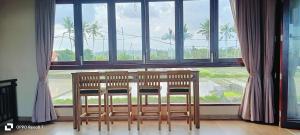 a table and two chairs in front of a large window at Otto Guest House Sukawati in Saba