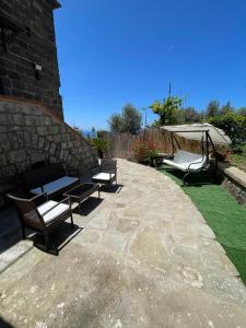 un patio con 2 bancos y una sombrilla en Liparulo Holiday House, en Massa Lubrense