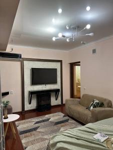 un soggiorno con divano e camino con TV di Квартира 1 ком Тауке хана 33 a Shymkent