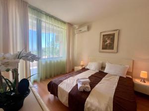 een slaapkamer met een groot bed en een groot raam bij Бяла Виста Бийч Апартментс B - Byala Vista Beach Apartments B in Byala