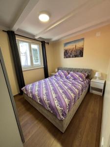 a bedroom with a bed with purple sheets and a window at Apartmani Bošnjak in Starigrad-Paklenica