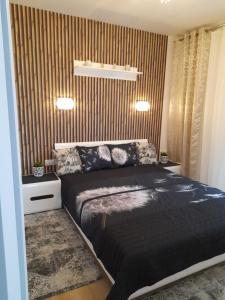 a bedroom with a black bed and a striped wall at Nadmorskie Apartamenty w Gąskach in Gąski