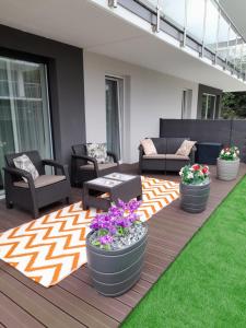 a patio with three large pots of flowers on a deck at Nadmorskie Apartamenty w Gąskach in Gąski
