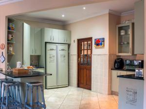- une cuisine avec des placards verts et un réfrigérateur dans l'établissement Mind-Body-Soul Guesthouse on Featherbrooke Estate, Krugersdorp, South Africa, à Krugersdorp