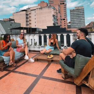 a group of people sitting on benches on a roof at Rodex Hostel Tucuman in San Miguel de Tucumán