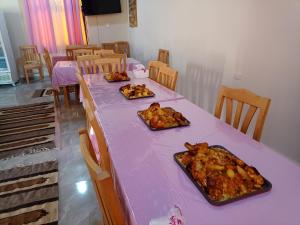 una mesa púrpura con tres platos de comida. en Rahala Safari Hotel en Qasr Al Farafirah