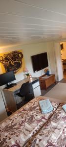 1 dormitorio con 1 cama, escritorio y TV en Sokkelleilighet rett ved Saltstraumen, en Bodø