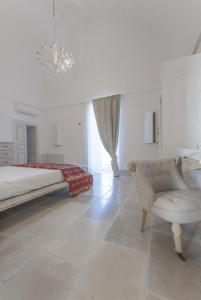 a white bedroom with a bed and a chair at Masseria Conca D'Oro in Ostuni