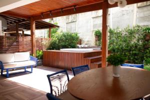 a patio with a table and chairs and a hot tub at In Mare Bali Flat Premium Sardenha by Qavi in Granja Beira Mar