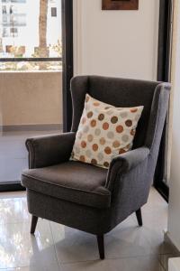 a gray chair with a pillow in a living room at Lazaros 1BDR Suite 3 min walk to Finikoudes beach in Larnaca +17 photos