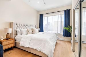 a white bedroom with a large bed with blue curtains at Central King Studio in Montreal