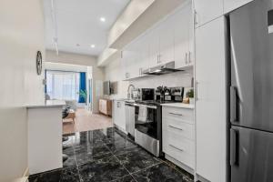 a kitchen with white cabinets and a black tile floor at Central King Studio in Montreal
