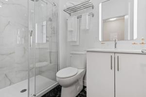 a white bathroom with a toilet and a shower at City Center 2BR Condo in Montreal +9 photos