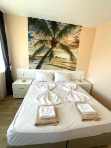 a bedroom with a white bed with a palm tree mural at Palms Studio in Sozopol, with free parking in Sozopol +7 photos
