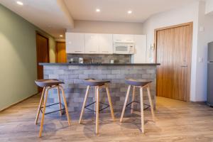 a kitchen with two bar stools in front of a counter at Capitalia Plaza Residences Reforma in Mexico City +19 photos