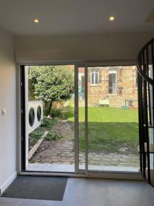 an open sliding glass door with a view of a yard at Charmante dépendance avec jardin in Vaux-sur-Seine