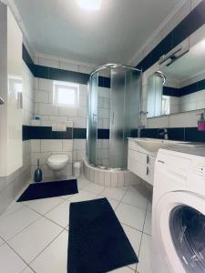 een badkamer met een douche, een toilet en een wasmachine bij Apartman Kiss in Jajce