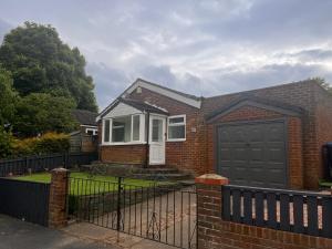 a brick house with a black door and a fence at Amani Bungalow in Brandon