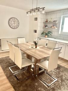 een eetkamer met een houten tafel en witte stoelen bij Apartman Kiss in Jajce