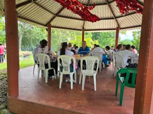eine Gruppe von Menschen, die an einem Tisch in einem Pavillon sitzen in der Unterkunft Llanitos de Aurora in Ibagué