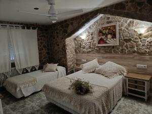 Un dormitorio con dos camas y una pared de piedra. en Casa Rural Outeiro, en Outeiro
