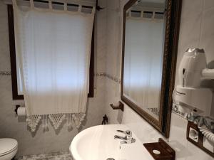 W łazience znajduje się umywalka, lustro i toaleta. w obiekcie Casa Rural Outeiro w mieście Outeiro