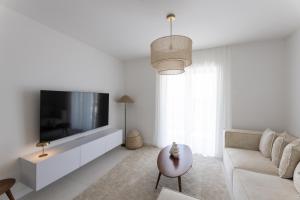 een witte woonkamer met een tv en een bank bij Olive apartment in Kaštela