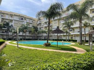 a large apartment building with a swimming pool and palm trees at The garden corner in Bouznika