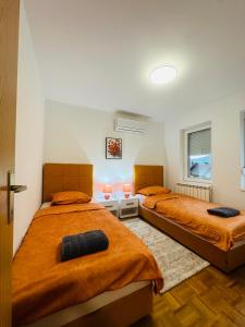 2 bedden in een slaapkamer met oranje lakens bij Vila Mariam&Maid in Sarajevo