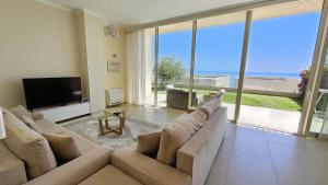 a living room with couches and a tv and large windows at Villa Harmony Green Coast, Palase in Himare