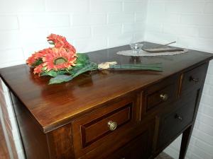 a wooden dresser with a bouquet of flowers on it at La Cueva in Ancona