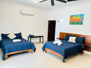 a bedroom with two beds with blue sheets and a fan at Departamentos Blue Bacalar in Bacalar