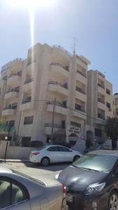 a parking lot with cars parked in front of a building at Al Khaleej Hotel Apartments in Amman