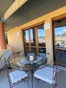 uma mesa de vidro e cadeiras num quarto com janelas em Appartement 02 Vue Panoramique -WIFI- Parking privé -NICE em Nice