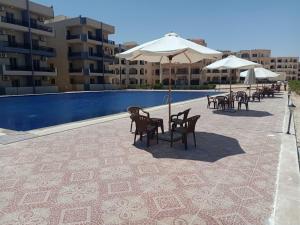 a patio with chairs and umbrellas next to a pool at قرية بلوباى مرسي مطروح in Marsa Matruh