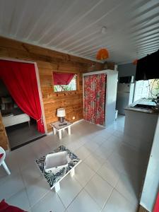 a living room with a red curtain and a kitchen at Rêve de Cabane in Capesterre-de-Marie-Galante +10 photos