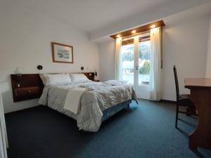 - une chambre avec un lit, un bureau et une fenêtre dans l'établissement Hotel Crismalu, à San Martín de los Andes