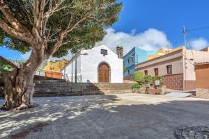 Un árbol sentado frente a un edificio con una iglesia. en Casa Los Holandeses, en Buenavista del Norte