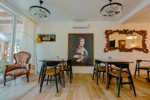 a dining room with two tables and chairs and a painting at Villa Loredan in Shkodër
