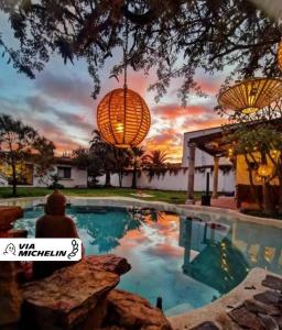 a person sitting next to a swimming pool with a sunset at Casa Mer, el oasis de la música y el agua in Tequisquiapan