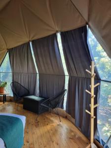 namiot z łóżkiem i 2 krzesłami w obiekcie Refugio La Paz EcoGlamping w mieście San Ramón