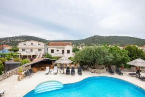 a villa with a swimming pool and mountains in the background at Family-friendly apartments with swimming pool Vinisce, Trogir - 22873 in Vinišće
