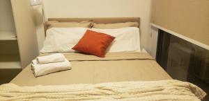 Bett mit orangefarbenem Kissen und weißen Kissen in der Unterkunft Studio Ben in São Paulo