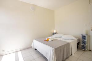 a white bedroom with a bed with flowers on it at Appartement les pieds dans l'eau in Sainte-Anne