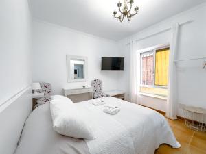 a white bedroom with a bed and a window at Hostal Habitaciones & Suites Don Pepín in Málaga