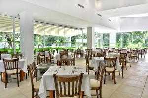 a restaurant with white tables and chairs and windows at Villas Holidays in Primorsko