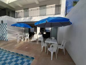 eine Terrasse mit Tischen, Stühlen und blauen Sonnenschirmen in der Unterkunft Villamagan in Carmen de Apicalá